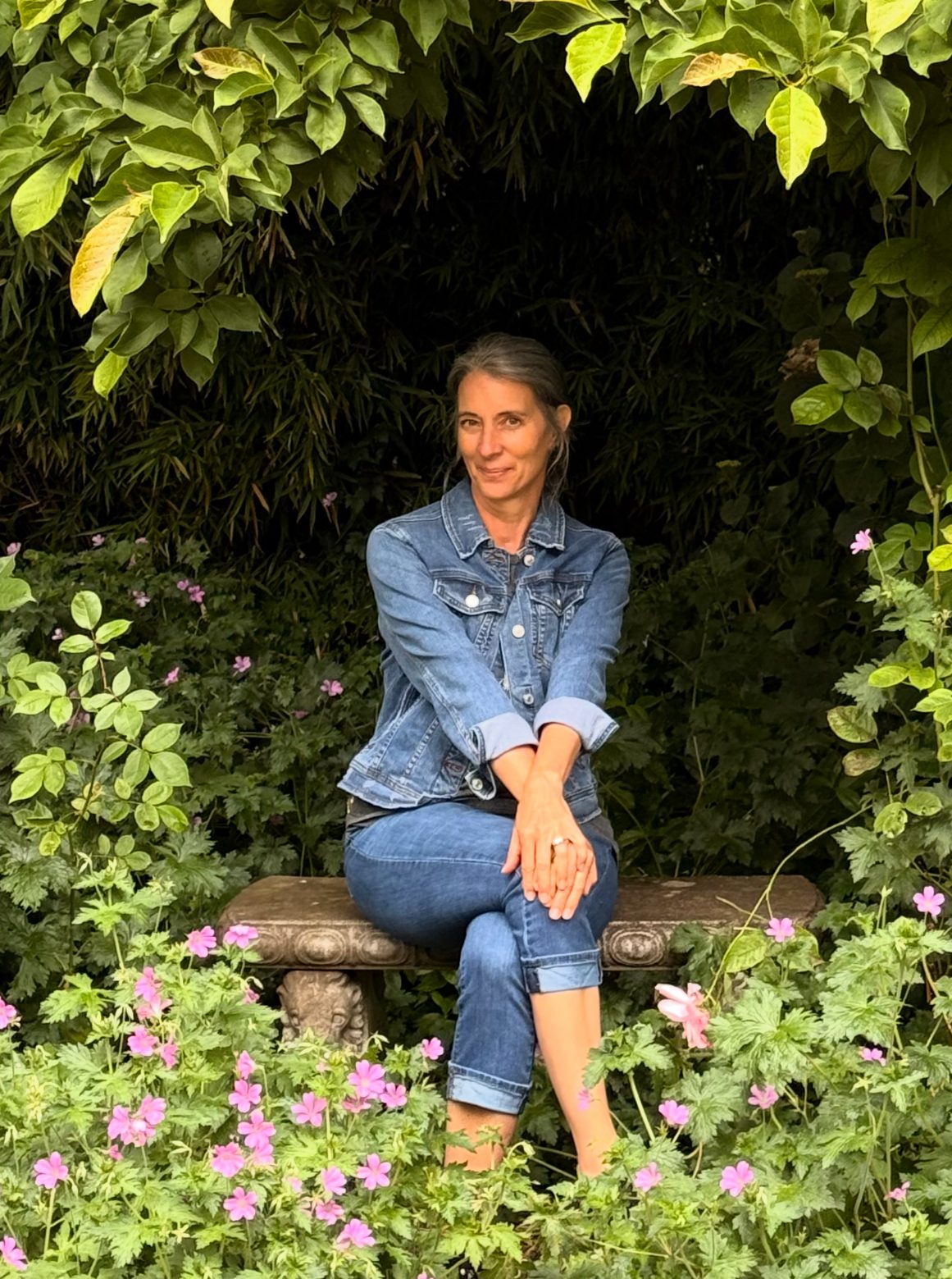 Susette, founder of Her Sanctuary, sitting on a bench in the garden